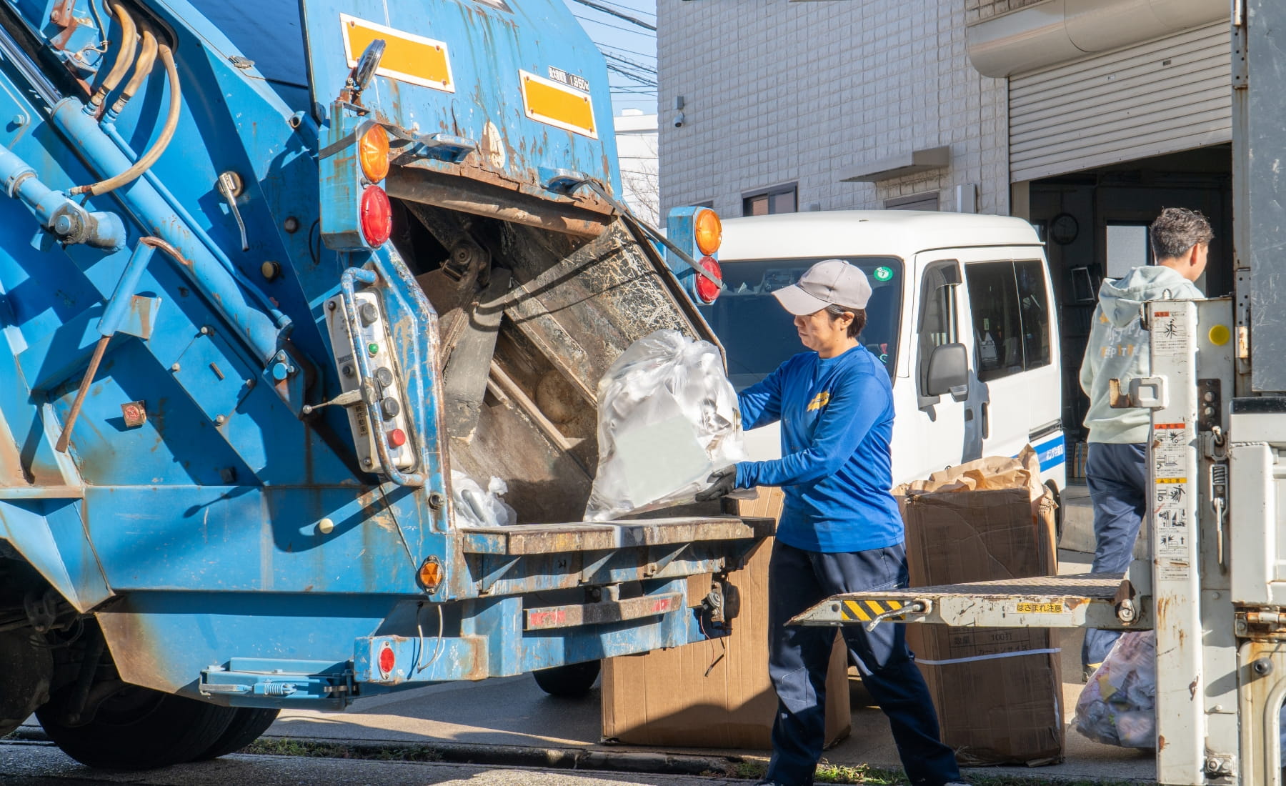 作業員がごみ収集車で廃棄物を処理している様子